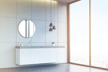Side view of a bathroom sink with round mirror on tiled wall, co