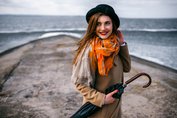 Redhead girl in hat with umbrella by the sea