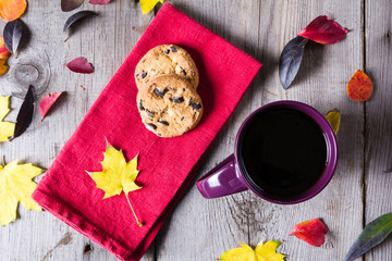 Cup of coffee surounded by red, purple and yellow fall leaves