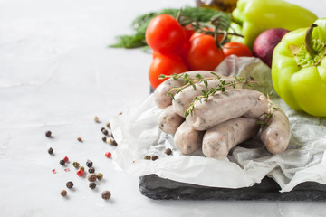 crude sausages and vegetables on a table, selective focus