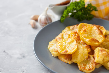 potatoes baked by slices in a plate on a table, selective focus
