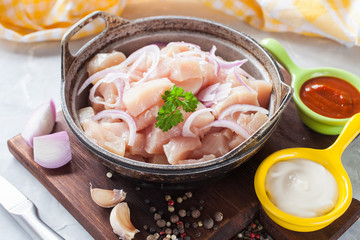 the meat of chicken cut with pieces in a frying pan on a table, selective focus