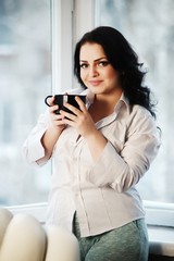 Portrait of young woman holding a cup of coffee.