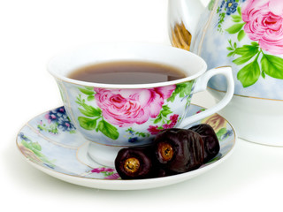 Dried dates and  cup of black tea. Isolated on white background