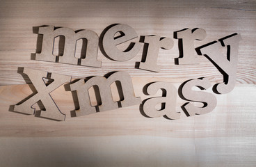 The greeting message "merry Xmas" composed volumetric letters on wooden background.
