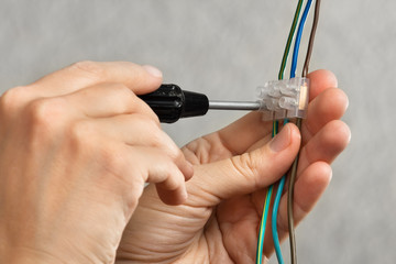 hands connecting wires in terminal block with screwdriver
