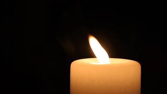 brennende Kerze wird im Dunkeln ausgepustet