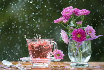 Cup of tea and pink flowers under the rain