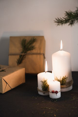 Christmas decorations on tha table, lit candles and gifts