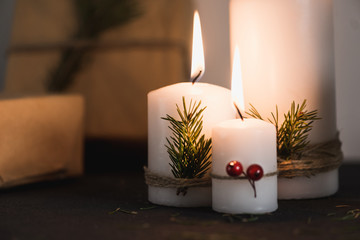 Christmas decorations on tha table, lit candles and gifts