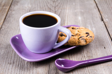Purple coffee cup with saucer, spoon on gray wooden table