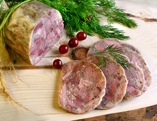 Homemade headcheese with dill and cranberries on a wooden board