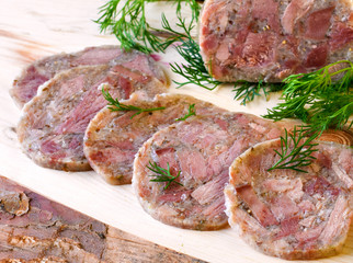 Homemade headcheese with dill and cranberries on a wooden board