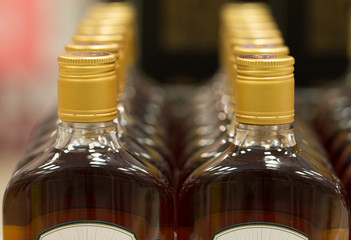 Top of plastic bottles with cognac or brandy standing in the liquor store. From the front.