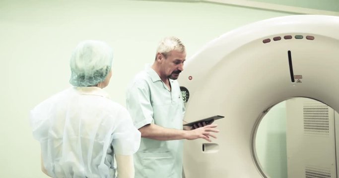 Doctor talks calms female patient before CT MRI scanning 4k video. Medical equipment: computed tomography machine in diagnostic clinic