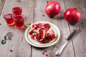 Whole and broken red ripe juicy pomegranates on rustic wooden unpainted table