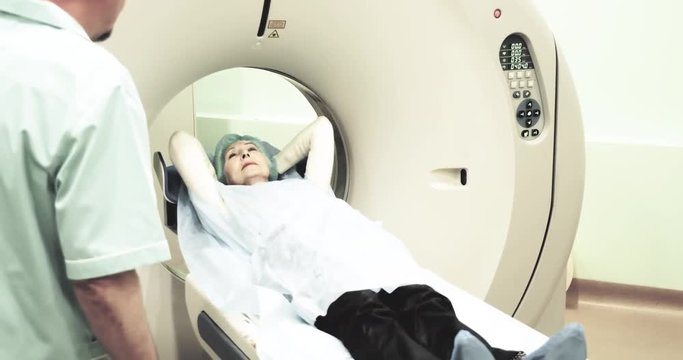 Female patient on CT MRI scanner 4k video. woman moving on computed tomography in diagnostic clinic, doctor talking