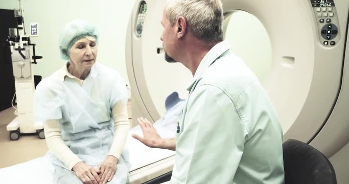 Doctor talks calms female patient before CT MRI scanning 4k video. Elderly woman listens to instructions before using medical equipment: computed tomography in diagnostic clinic