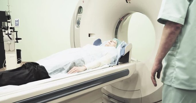 Female patient on CT MRI scanner 4k video. woman moving on computed tomography in diagnostic clinic, doctor talking