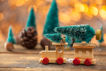 Miniature Toy Train Towing A Christmas Tree On A Wooden Backgrou