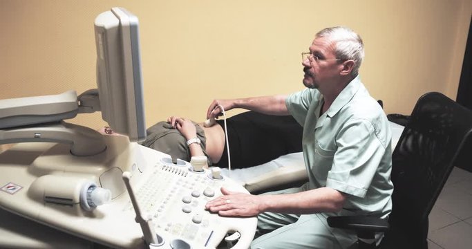 Doctor doing medical ultrasound on woman patient belly 4k video in diagnostic clinic. Doctor talking, scanner machine control panel