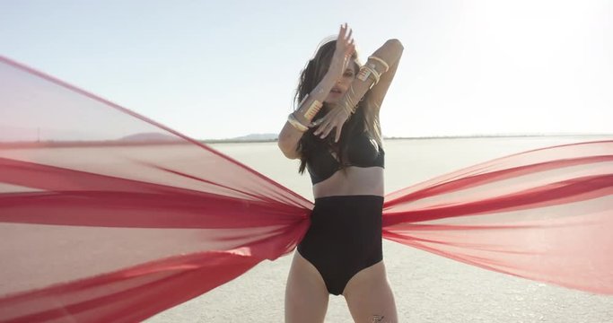 Girl with a fabric walking and dancing in the desert