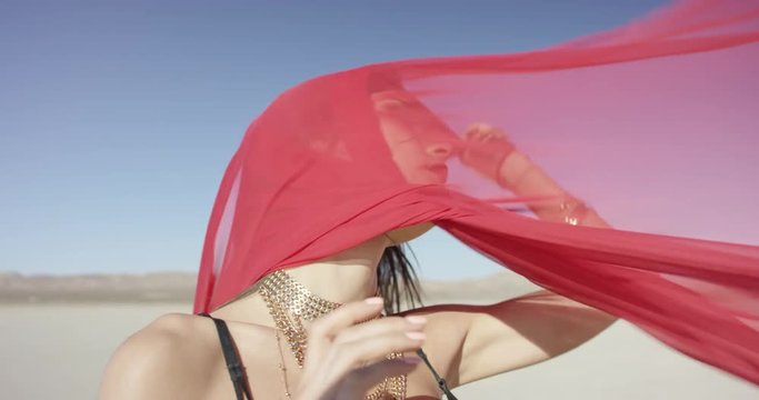 Girl with a fabric walking and dancing in the desert