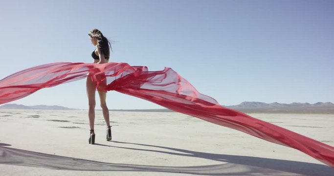Girl with a fabric walking and dancing in the desert