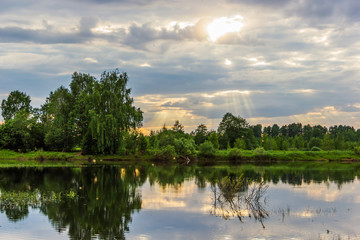 Fototapeta na wymiar The sun's rays breaking through the clouds. The River Mologa.