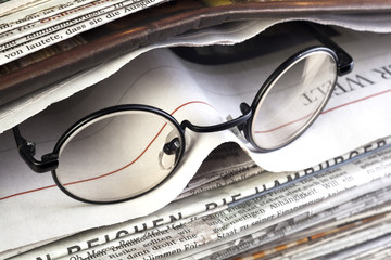 stack of newspaper with readinf glasses