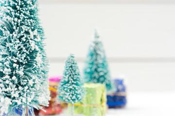 Christmas trees with white snow and gift boxes - selective focus