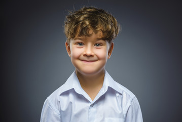 Happy child. Closeup Portrait of handsome boy smiling isolated on grey background