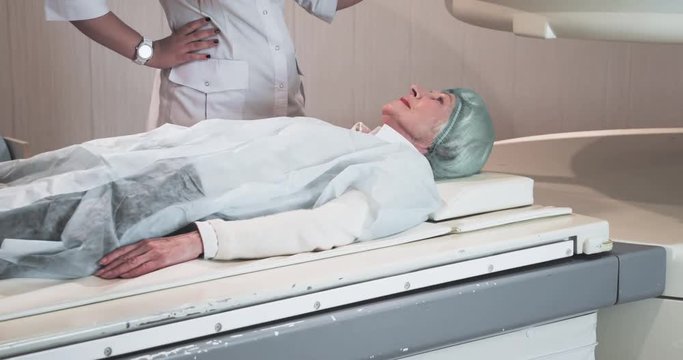 Woman on MRI scanner 4k video. Nurse operate medical equipment: magnetic resonance imaging machine in diagnostic clinic