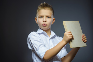 Handsome little stressed boy with book isolated on gray background