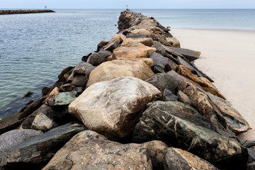 Wall of piled rocks on sandy beach