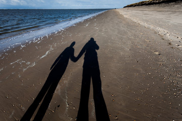 Shadow of couple holding hands on beach