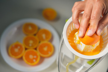 Closeup on hand of a person squeezing healthy orange juice mix