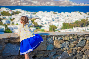 Fototapeta premium Adorable little girl in Mykonos town background amazing view of traditional white houses