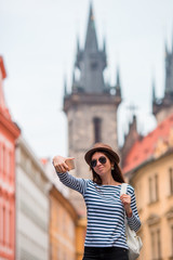 Happy young woman taking selfie background famous castle in european city. Caucasian tourist walking along the deserted streets of Europe. Warm summer early morning in Prague, Czech Republic