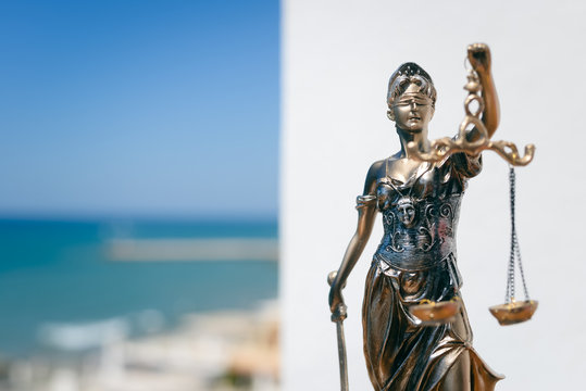 Sculpture of justice or themis goddess on outdoors bright blue sky background