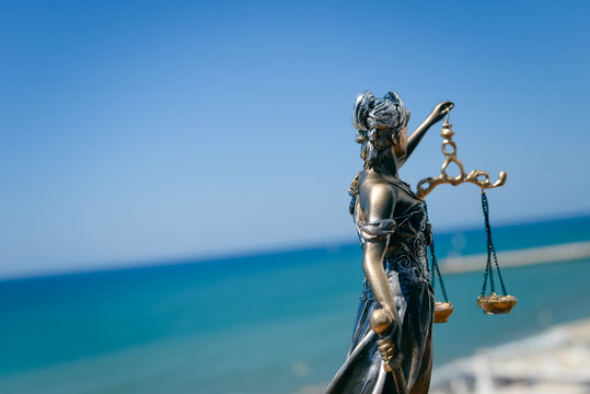 Back side view of Themis - Lady of Justice on blue sky background