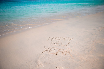 Happy New Year written in the white sand