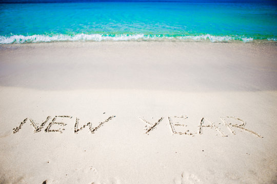 Happy New Year written in the white sand