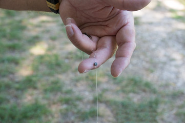 In hand of fisherman are hook with a sinker close up.