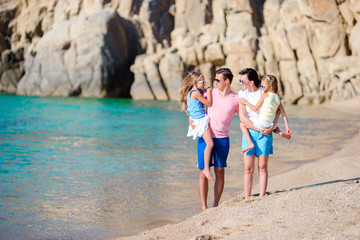 Happy beautiful family with kids walking together on tropical beach during summer vacation