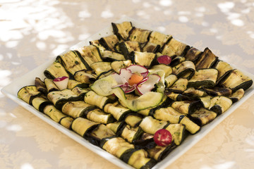 small samples of slices of eggplant and zucchini with olive oil, salt and pepper served on square plate