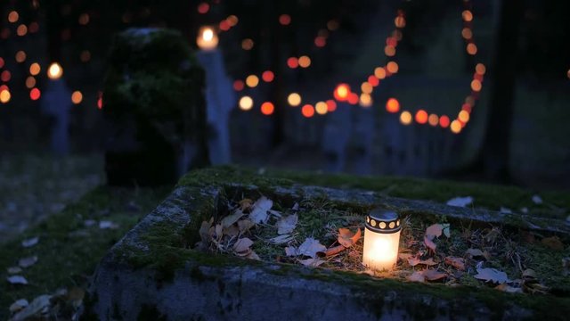 Cemetery at night with colorful candles for All Saints Day. All Saints' Day is a solemnity celebrated on 1 November by the Catholic Church. Static shot. 4K