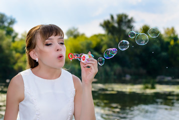 Happy young bride blowing bubble to celebrate