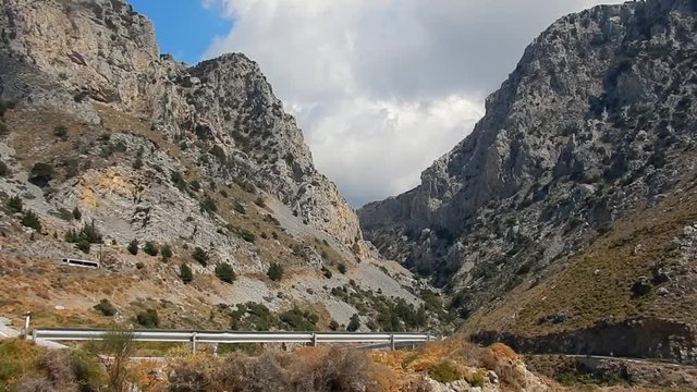 A route with cars and pullman into a gorge in a cloudy day, Crete, Greece