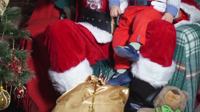 Closeup Santa shows baby toy on the Christmas tree